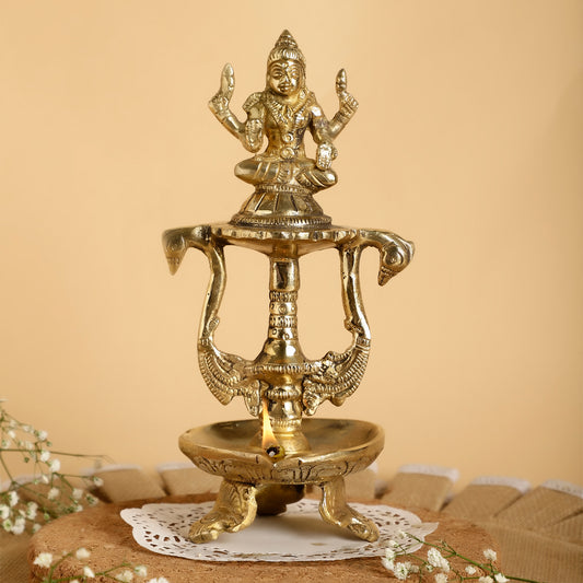 Brass lamp with a deity figure on a beige background