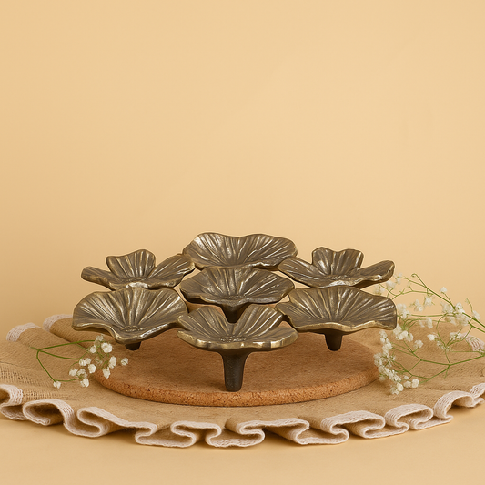 Decorative metal leaf-shaped tray on a beige surface with a plain background
