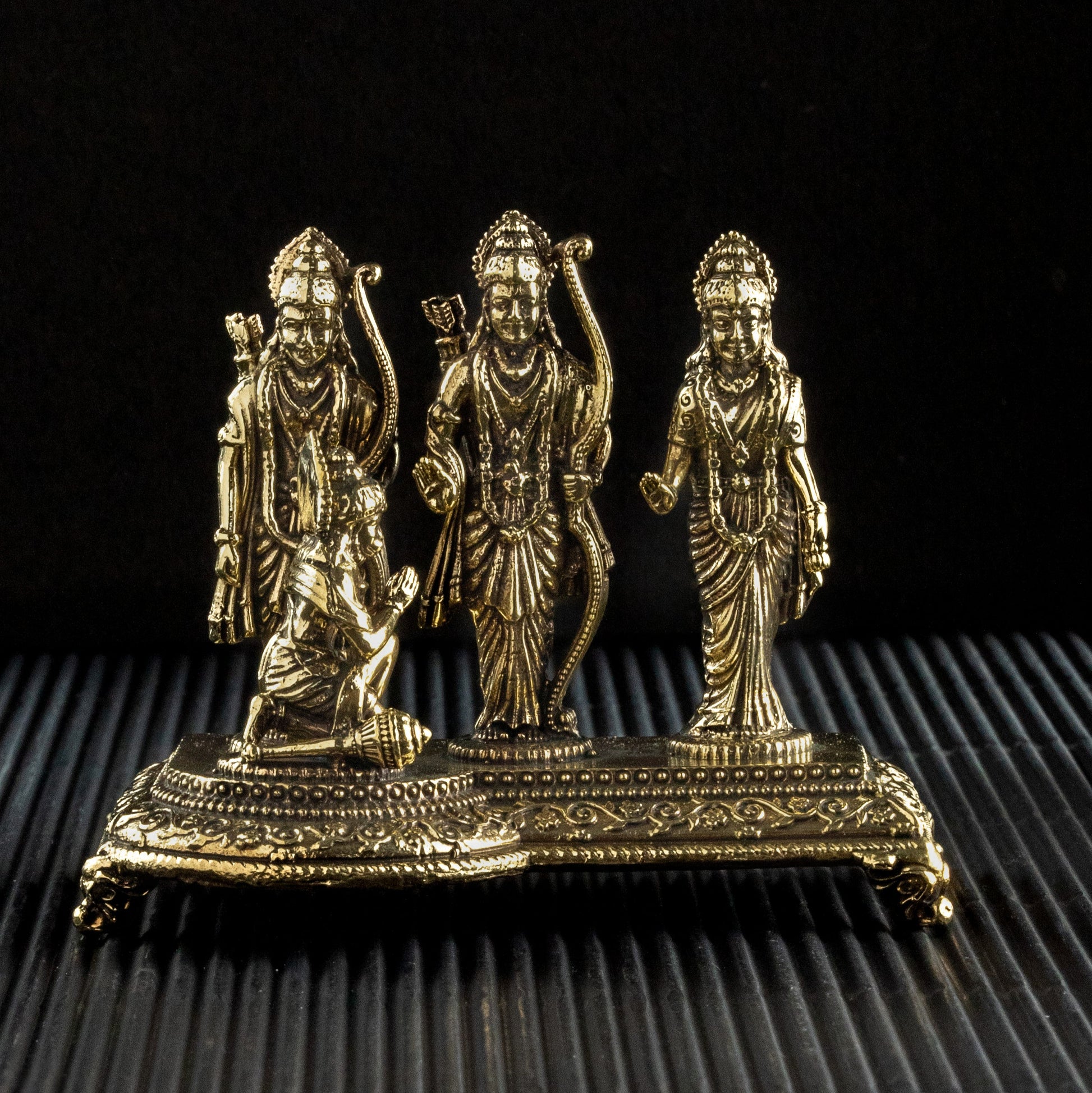 Bronze statue of three figures on a textured black surface