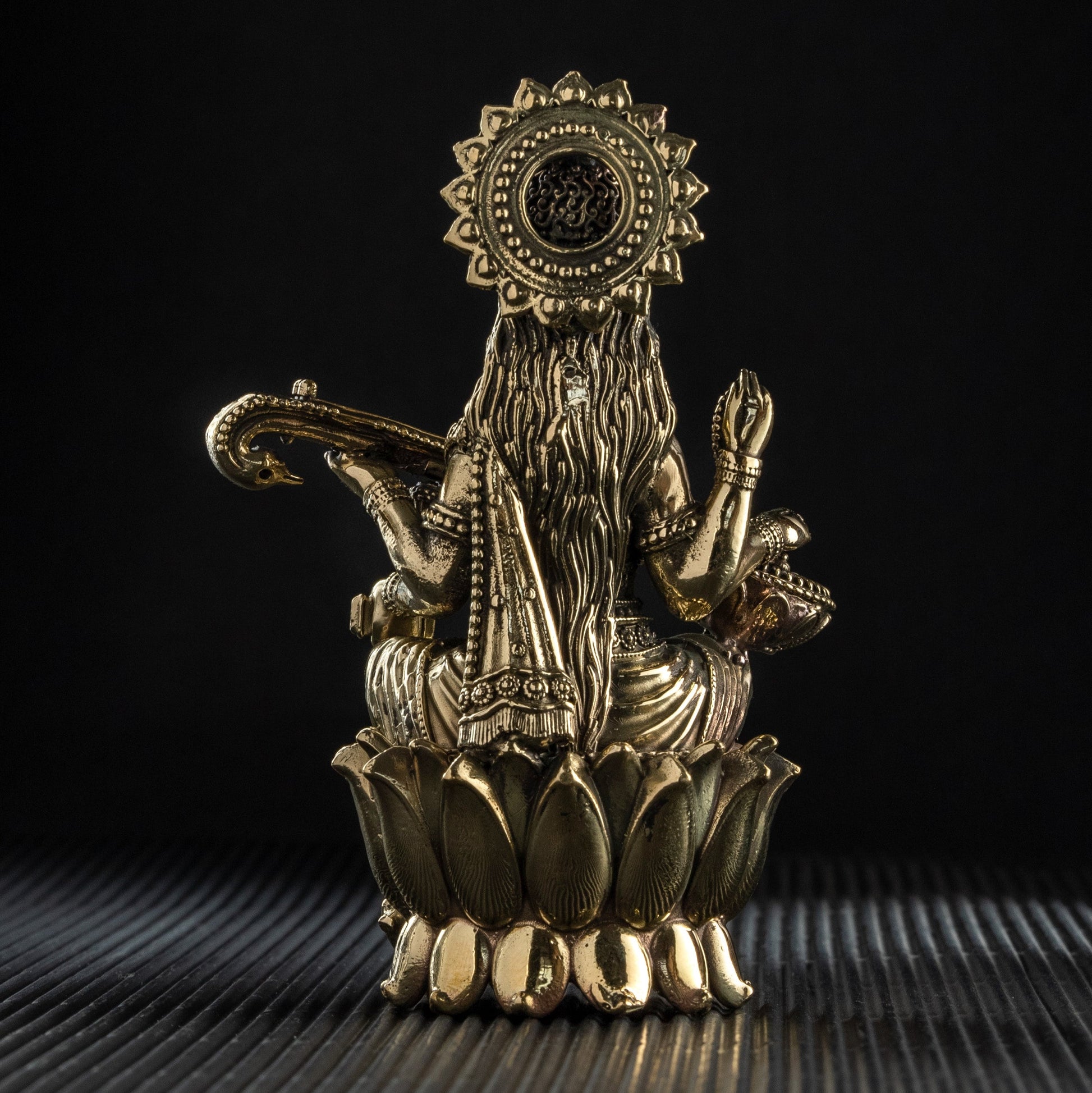 Decorative brass statue on a textured surface with a black background