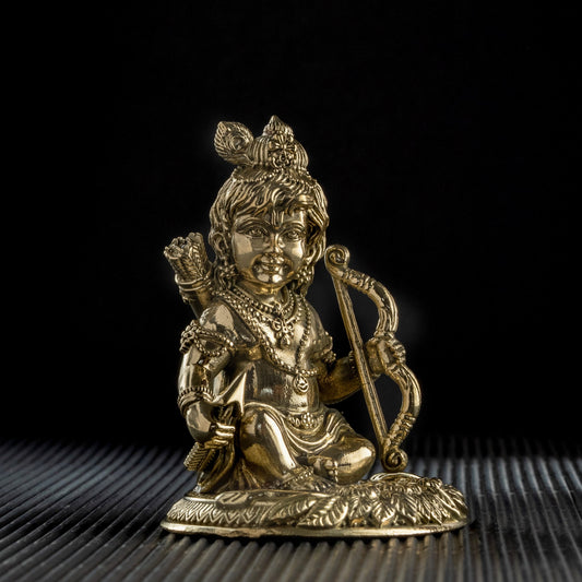 Gold-colored statue of a seated figure with a weapon on a black background