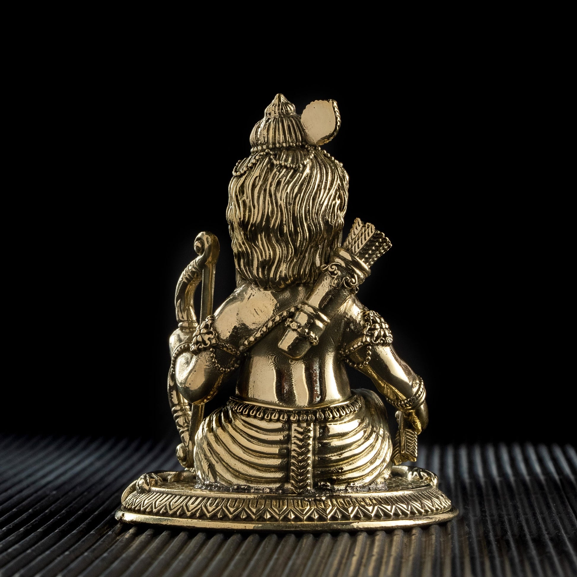 Brass statue of a seated figure with a dark background