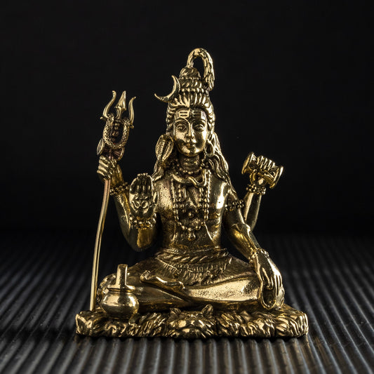 Gold-colored statue of a seated figure on a textured black surface