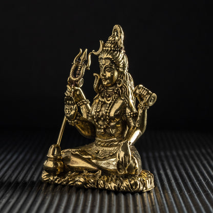 Gold-colored statue of a deity on a textured black surface