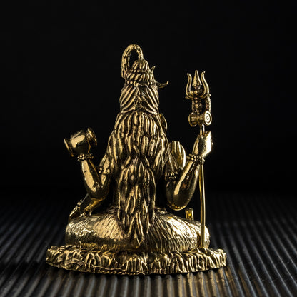 Gold-colored statue of a deity on a textured surface with a black background