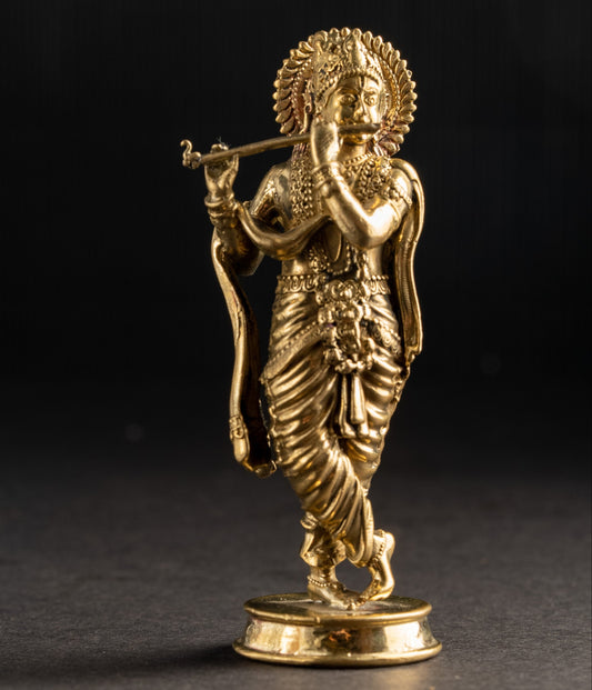 Gold-colored statue of a deity holding a flute on a dark background