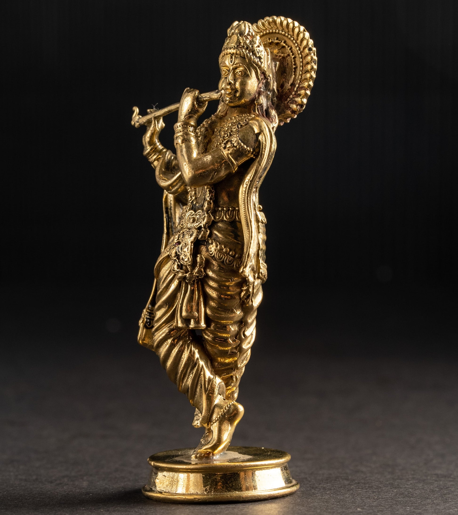 Gold-colored statue of a deity on a black background
