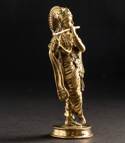 Gold-colored statue of a figure with a headdress on a dark background