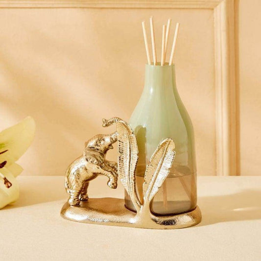 Decorative bottle with gold elephant and leaf design on a beige surface