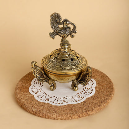 Decorative brass incense burner on a cork coaster with a white doily underneath