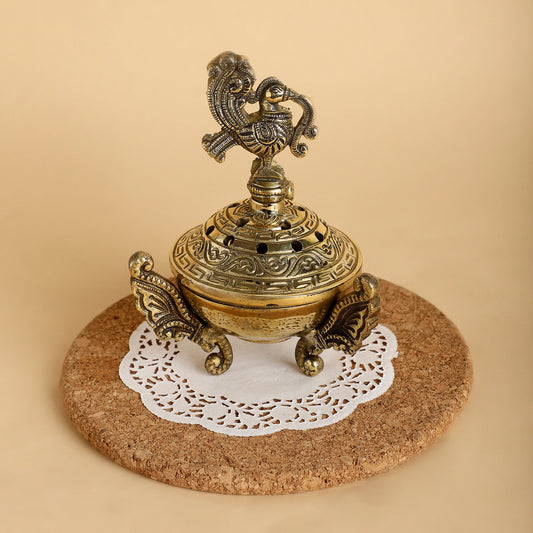 Decorative brass incense burner on a cork coaster with a white doily underneath