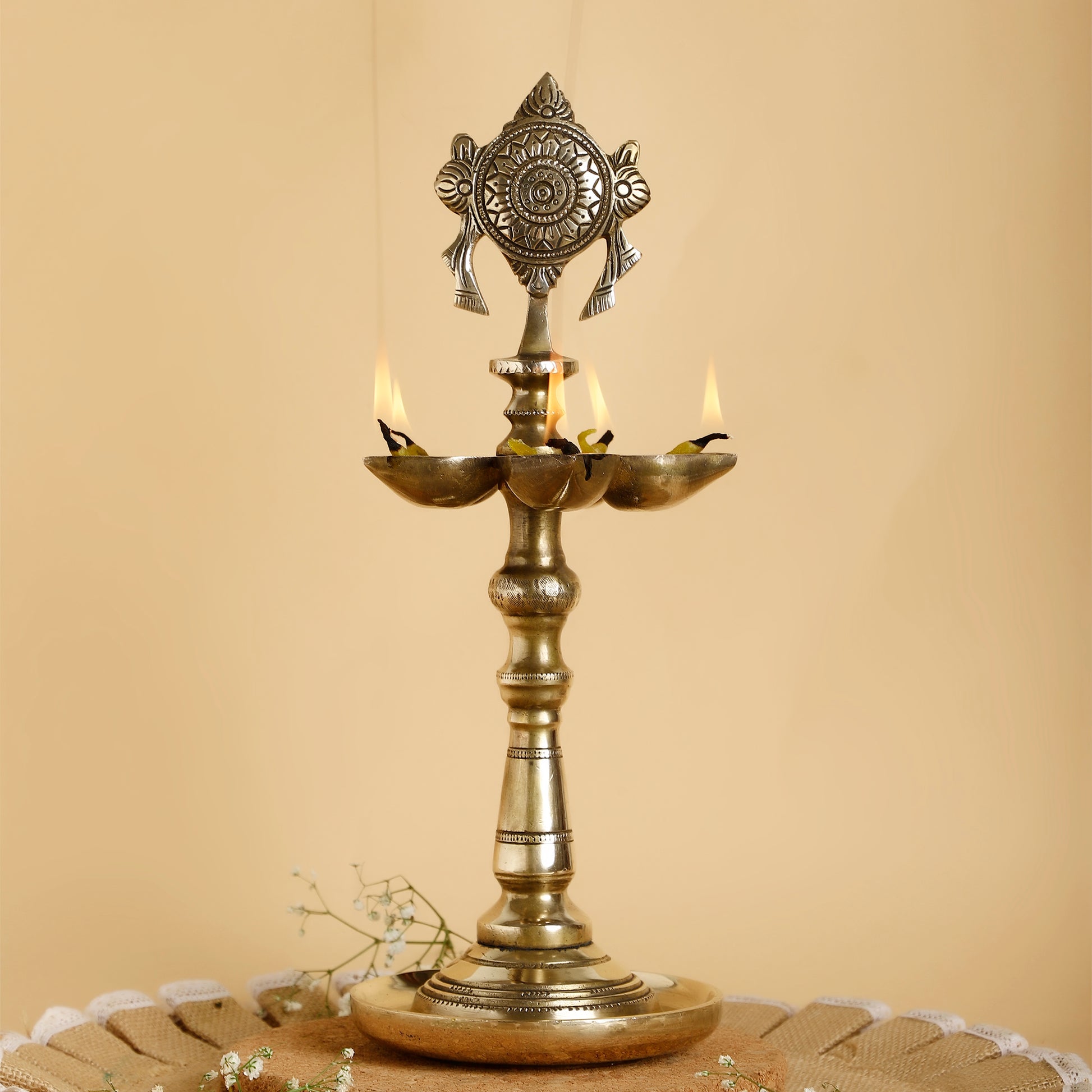 Decorative brass lamp with three candles on a beige background