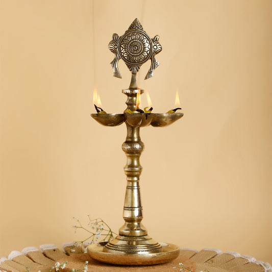 Decorative brass lamp with three candles on a beige background