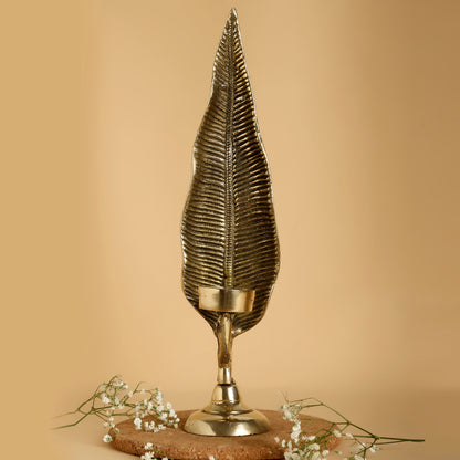 Decorative gold leaf-shaped candle holder on a beige background