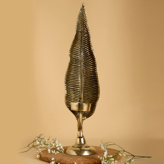 Decorative gold leaf-shaped candle holder on a beige background