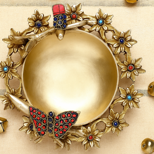 Decorative gold plate with floral designs and colorful butterfly on a beige background