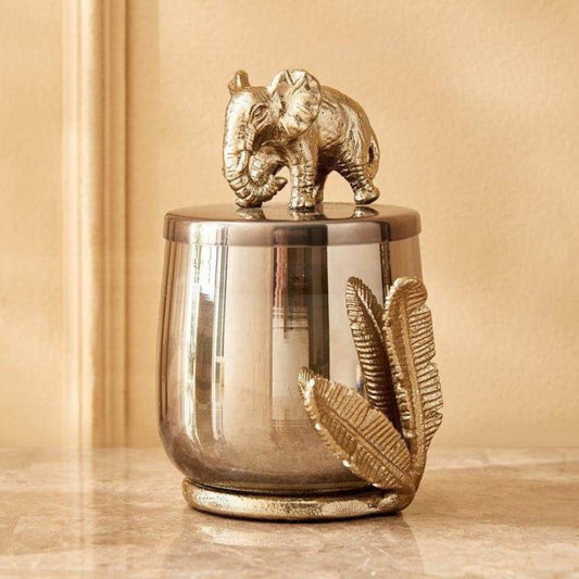Decorative jar with an elephant on top against a beige background
