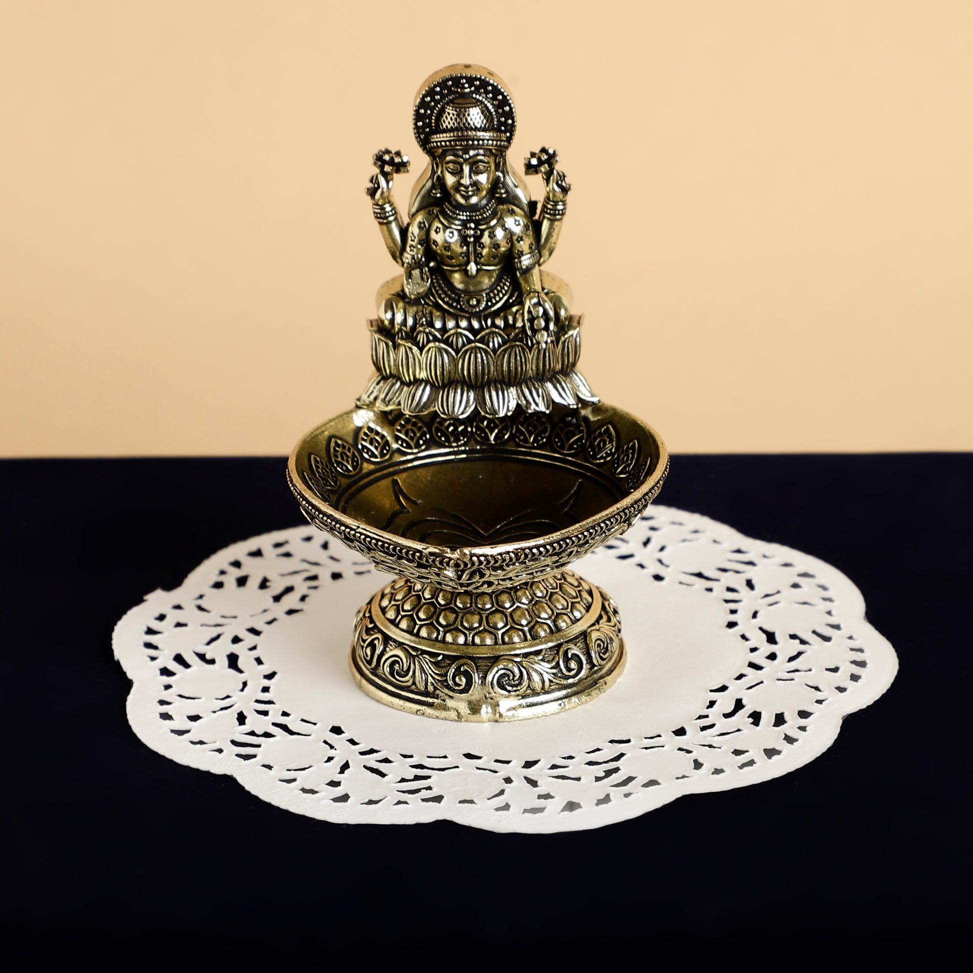 Decorative metal statue on a white doily with a beige background