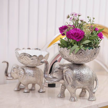 Decorative silver elephant with a bowl of flowers on a light background