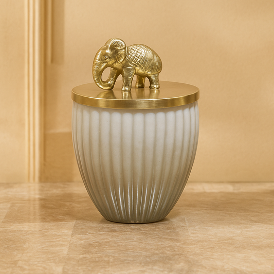 Decorative vase with a gold elephant on top against a beige background