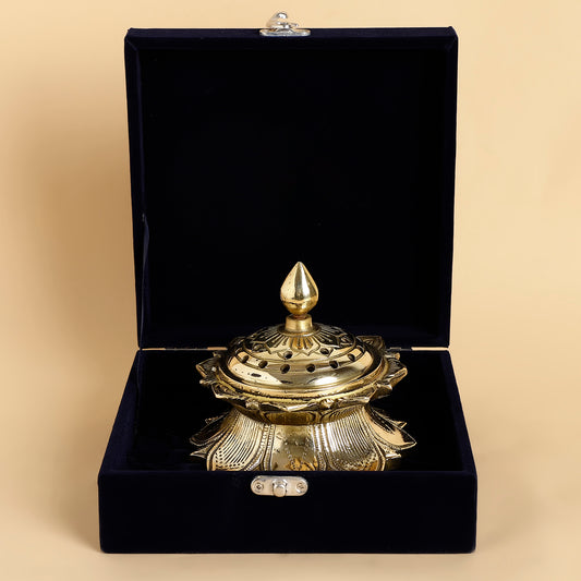 Gold decorative item in an open black velvet box on a beige background