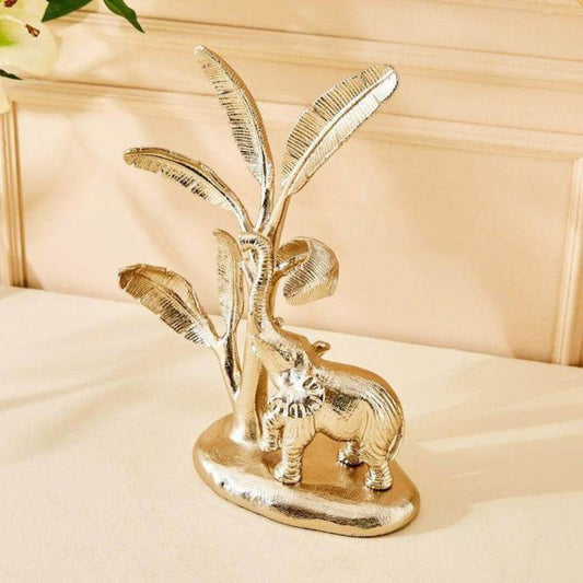 Gold elephant figurine with leaves on a beige surface