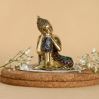 Gold Buddha statue with colorful gemstones on a beige background