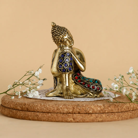 Gold Buddha statue with colorful gemstones on a beige background