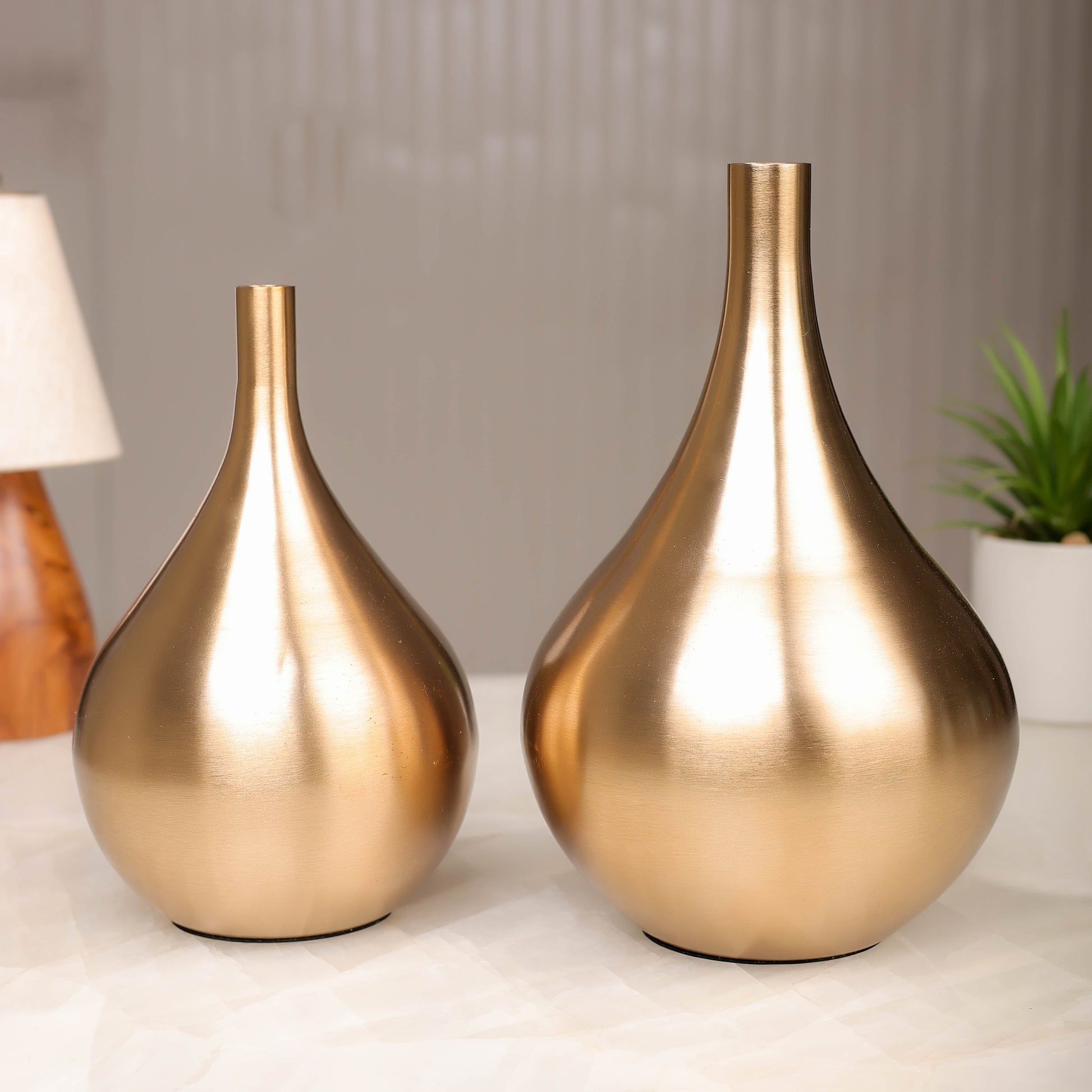 Two gold vases on a surface with a blurred background