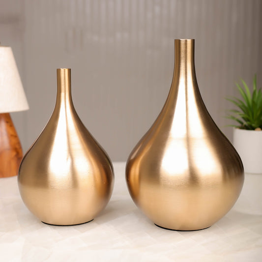Two gold vases on a surface with a blurred background