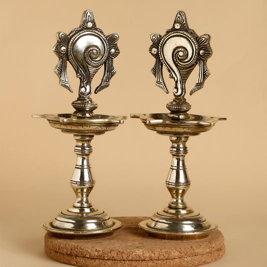 Two ornate silver candle holders on a beige background