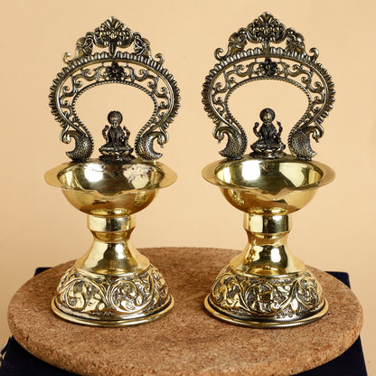 Two ornate brass lamps with intricate designs on a beige background