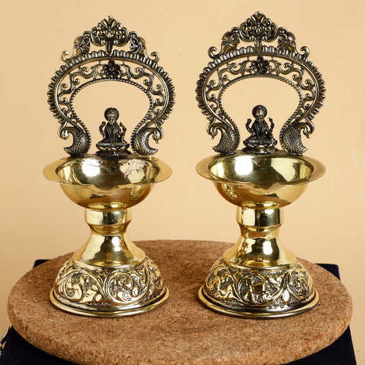 Two ornate brass lamps with intricate designs on a beige background