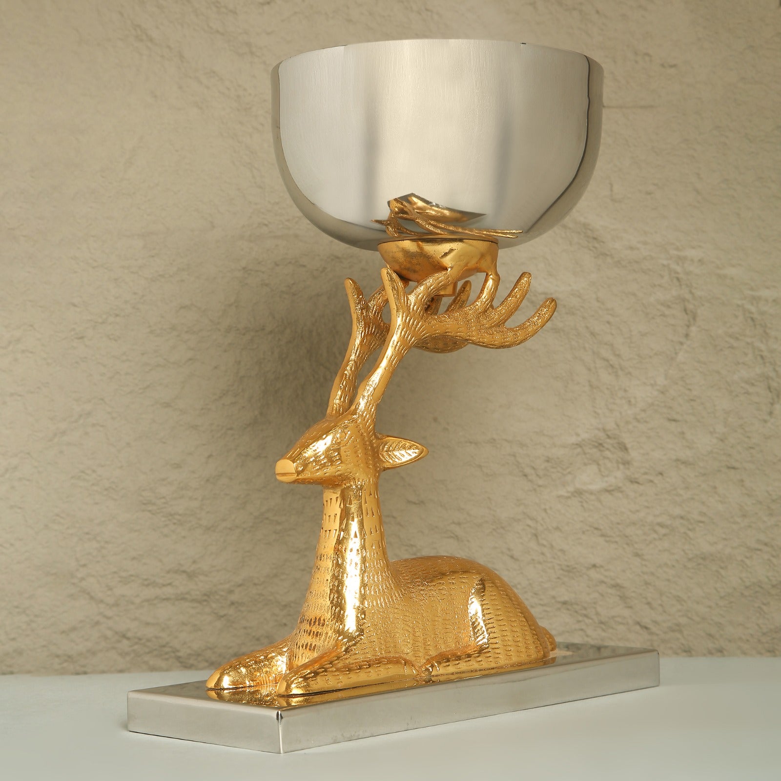 Gold deer-shaped candle holder with a silver bowl on a beige background