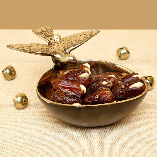 Brass bowl with dates and decorative elements on a beige background