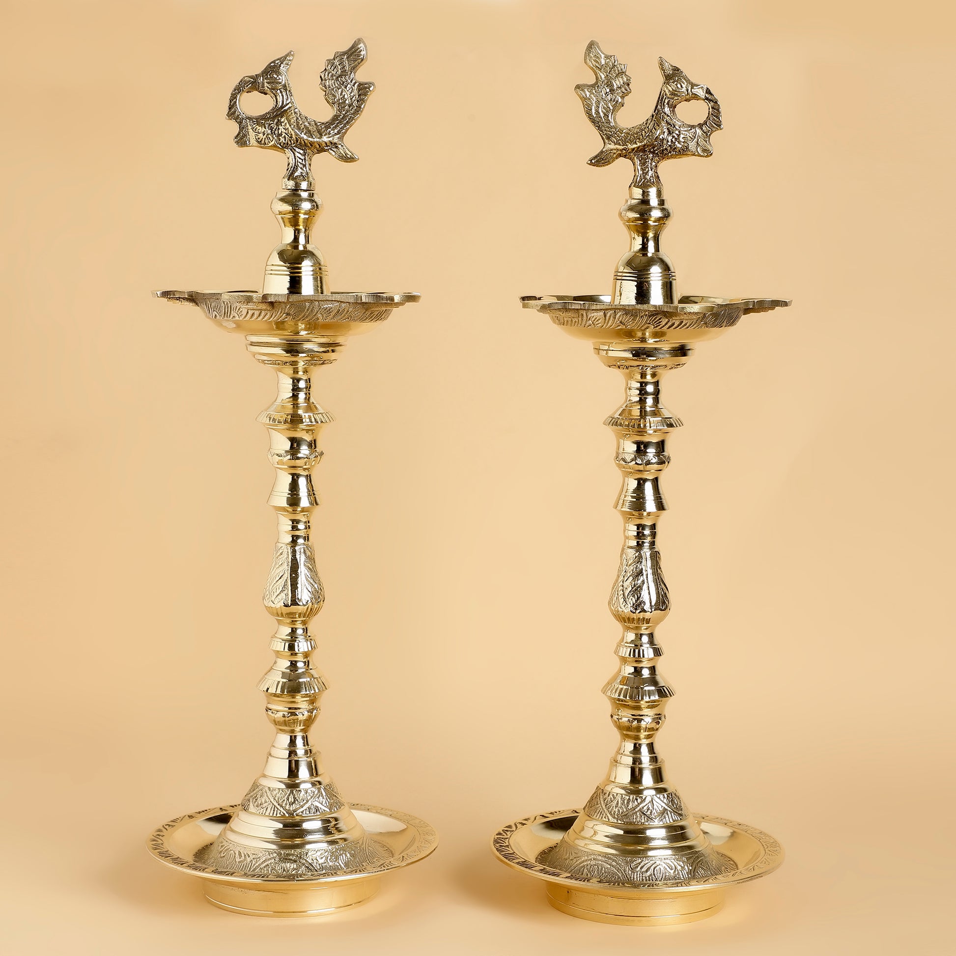 Two ornate brass lamps on a beige background
