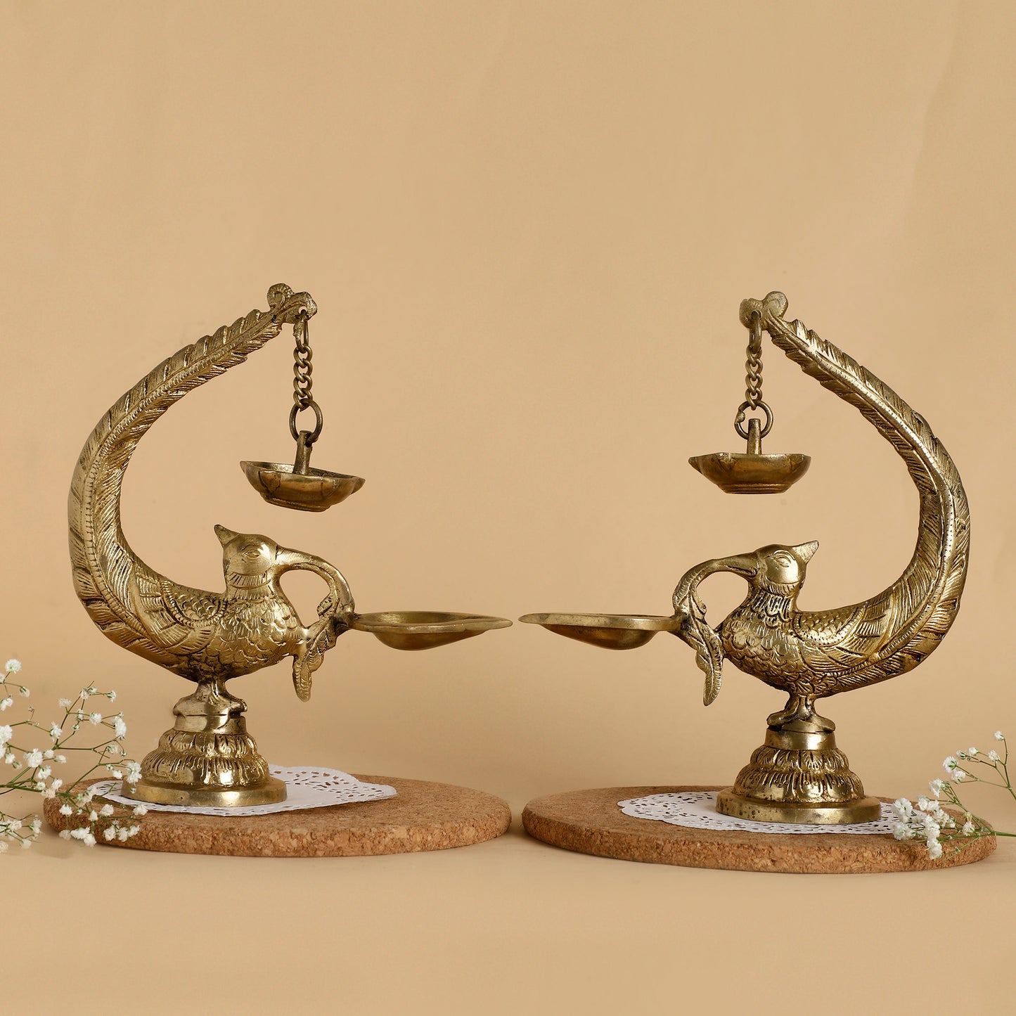 Decorative brass peacock-shaped lamps on a beige background