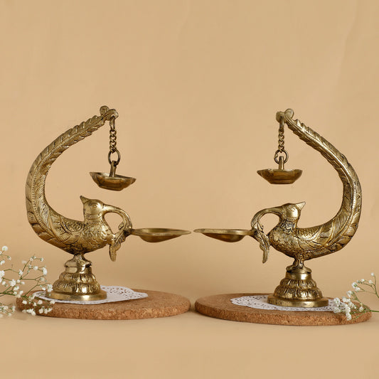 Decorative brass peacock-shaped lamps on a beige background