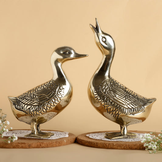 Two metallic duck sculptures on cork bases against a beige background