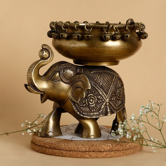 Bronze elephant sculpture with a bowl on its back against a beige background
