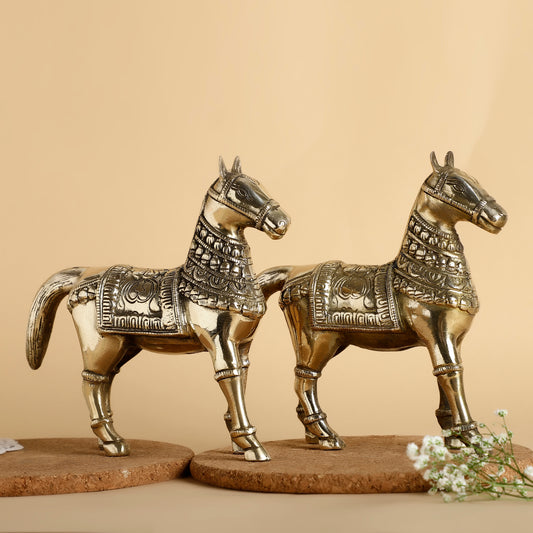 Two ornate brass horse statues on a beige background