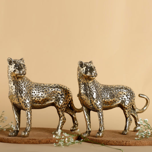 Two metallic leopard sculptures on a beige background