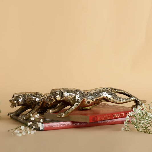 Decorative metallic panther sculpture on books with a beige background