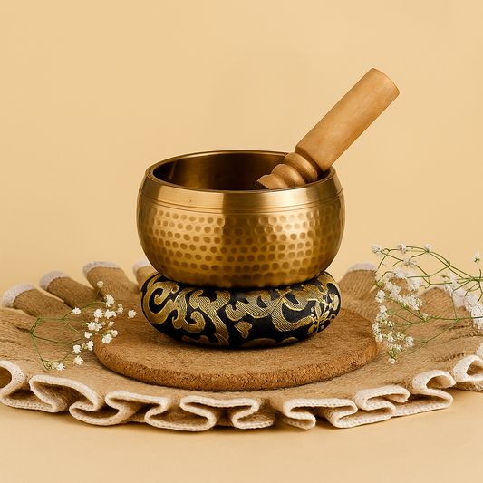 Brass singing bowl with wooden striker on a beige background